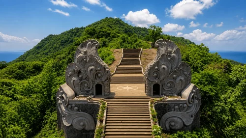 Sang Hyang Ambu Gate staircase with ornate stone carvings leading up a lush green hill under a bright blue sky in Bali