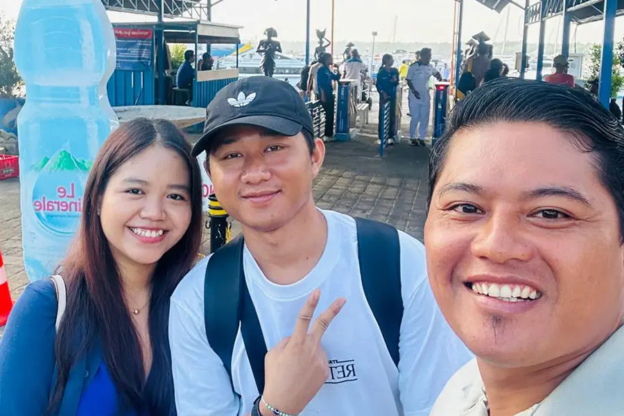 A professional local driver from a bali car rental service assisting a group of tourists as they prepare to depart for a day tour across the island | balitouristic.com