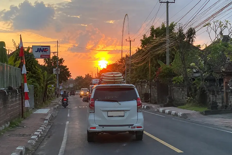 Airport transfer vehicle in Bali transporting travelers and surfboards from the airport to a beach resort.