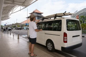 Surfers arriving in Bali with surfboards and using a private airport transfer service to reach their destination.
