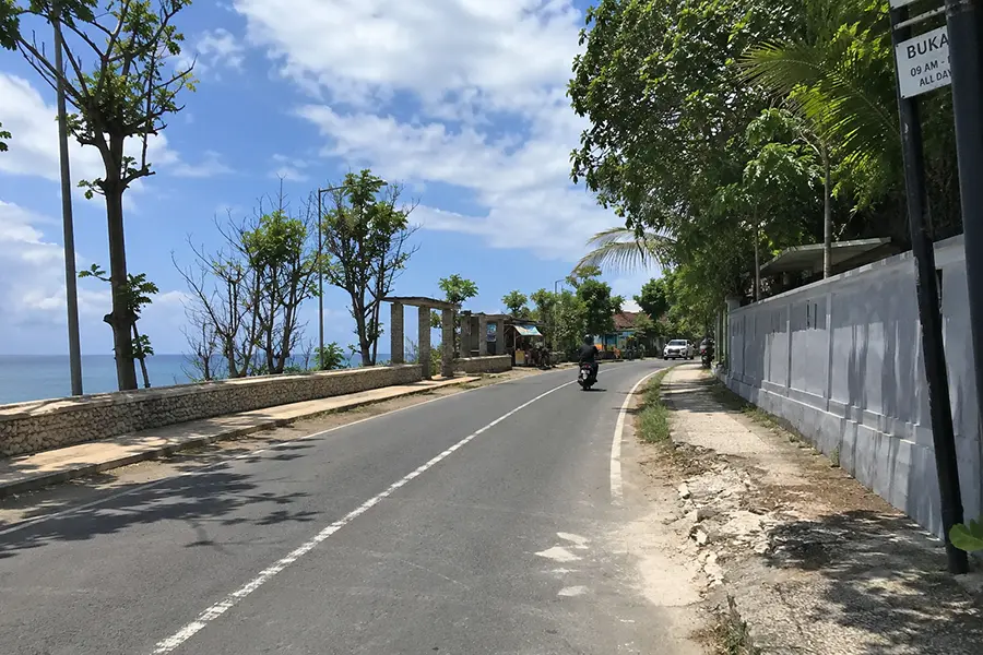 A quiet coastal road in balangan beach with ocean views, ideal for exploring the island on self-drive trips | balitouristic.com