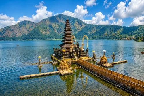 A peaceful view of Pura Segara Ulun Danu Batur beside the lake, featuring traditional Balinese temple architecture, calm waters, and misty mountain scenery, representing one of the hidden temples in Bali.
