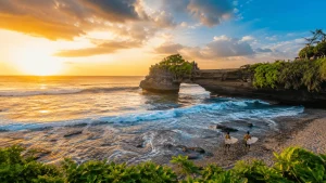 A scenic coastal view of Batu Bolong Beach featuring rolling surf waves, black sand shoreline, tropical sunsets, and a lively beach atmosphere popular with surfers and travelers in Bali.