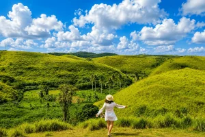 A breathtaking landscape view of Teletubbies Hill featuring rolling green hills, scenic valleys, blue skies, and peaceful tropical countryside scenery.