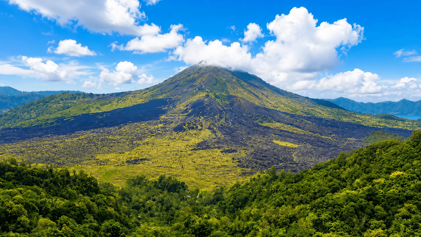 A breathtaking view of Mount Agung rising above lush tropical landscapes and morning mist, showcasing one of the most iconic and top attractions in Bali.