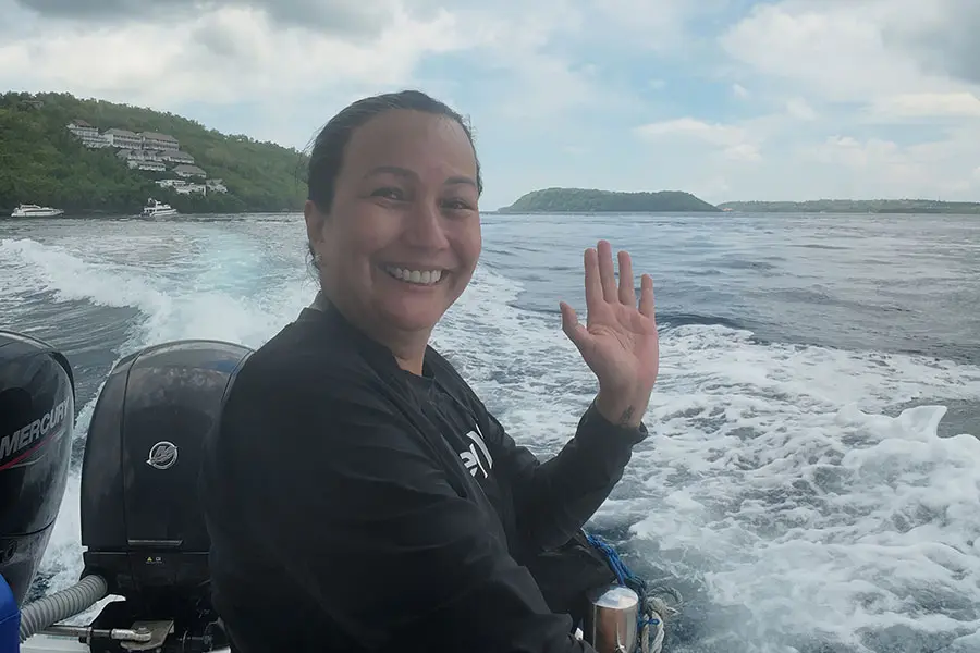 A smiling traveler waving excitedly from a speedboat after a thrilling blue lagoon snorkeling tour along the coast. | balitouristic.com