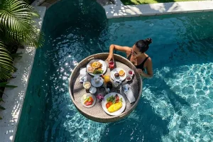 A rectangular morning food tray filled with healthy dishes floating in a pristine villa pool, perfect for a floating breakfast in Bali. | balitouristic.com
