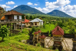 A peaceful countryside view of Guliang Kangin Village featuring lush rice fields, traditional Balinese homes, tropical greenery, and scenic rural landscapes surrounded by hills and nature.