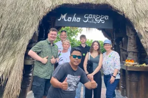 An international tour group posing together with their private tour driver at the scenic entrance of Maha Gangga Valley, showing the benefit to hire driver bali. | balitouristic.com