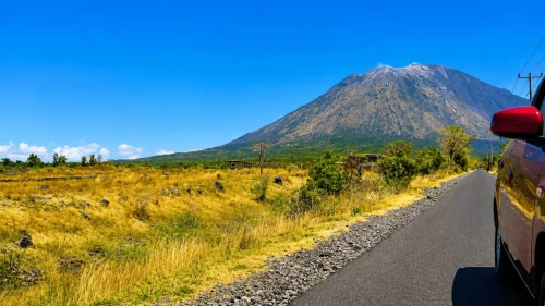 A stunning mountain landscape at Savana Nusu featuring rolling green hills, dramatic mountain views, tropical grasslands, and a peaceful highland atmosphere under clear skies.