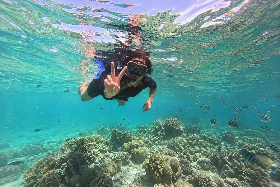 A tourist swimming underwater and closely interacting with a wild sea turtle during a scenic trip to gili islands snorkeling excursion. | balitouristic.com