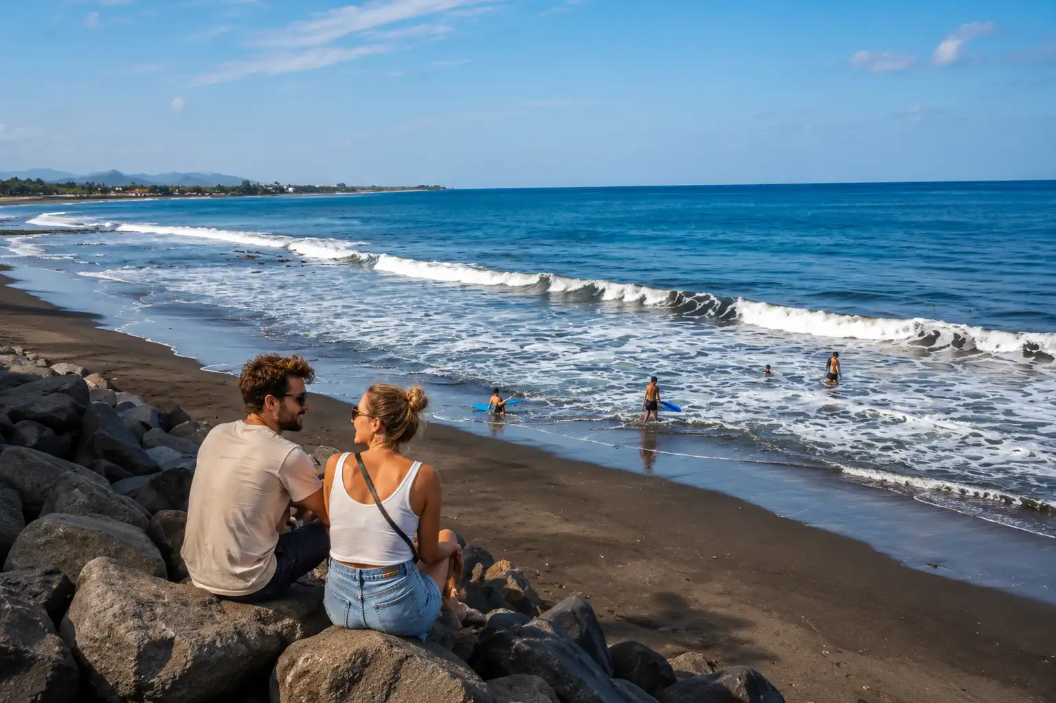 A happy couple sitting together on the black sand of Lebih Beach, enjoying the peaceful ocean view with gentle waves, swaying palm trees, and warm golden sunlight, creating a romantic and relaxing tropical beach atmosphere.