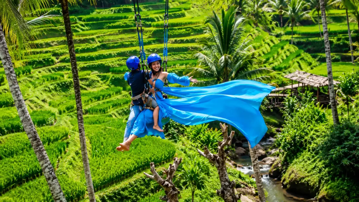 A traveler enjoying the iconic jungle Bali swing Ubud at Alas Harum Bali, soaring above lush rice terraces, tropical palm trees, and beautifully landscaped agrotourism gardens with breathtaking panoramic views of Ubud’s countryside.