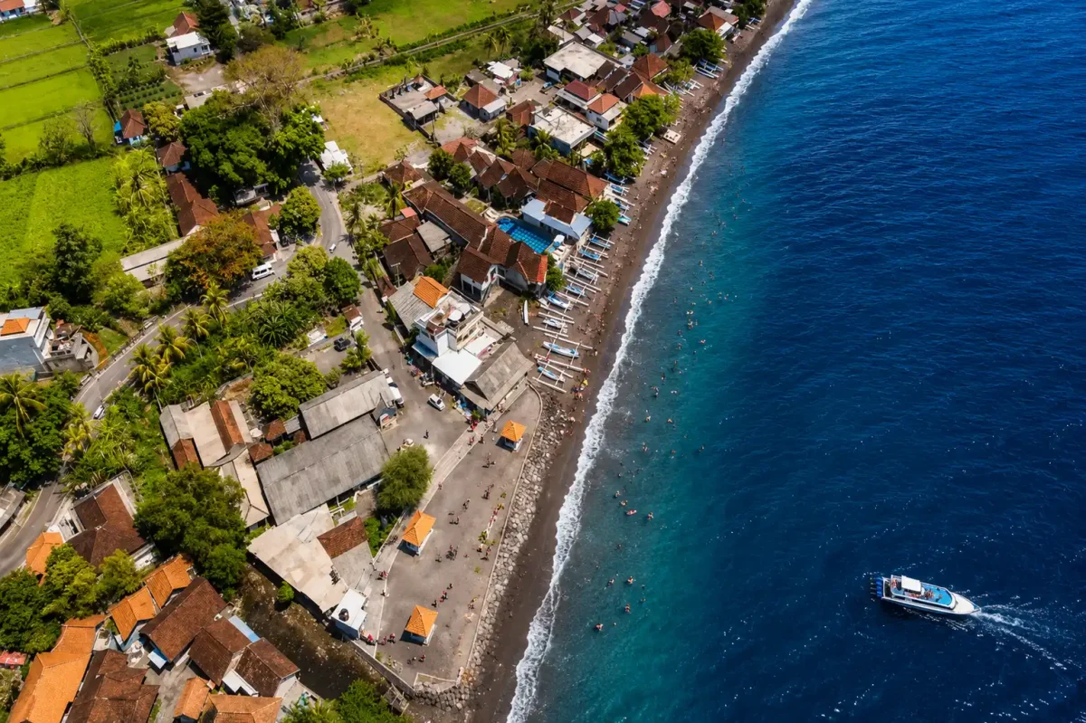 Scenic view of Amed Beach featuring colorful fishing boats, calm sea, and Mount Agung in the distance as one of Bali interest place.