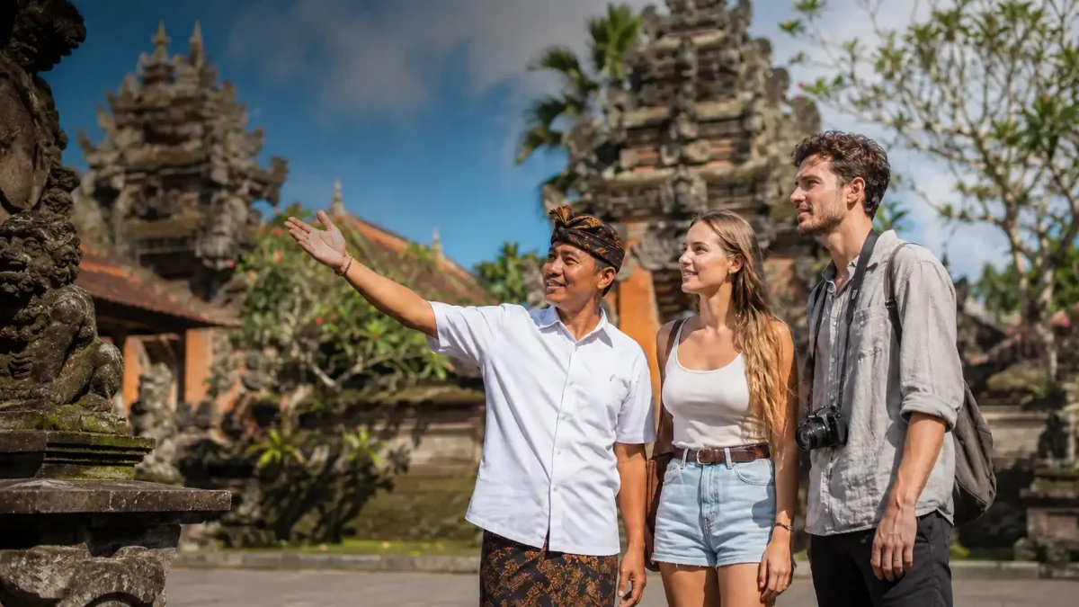 A professional local driver in Seminyak assisting travelers beside a comfortable modern vehicle, surrounded by tropical scenery and stylish resort areas, representing a reliable Bali Driver Seminyak service for private tours and island exploration.