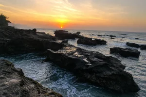 A stunning sunset over rugged black volcanic rock shelves and tide pools along the ocean shore at nyanyi beach.