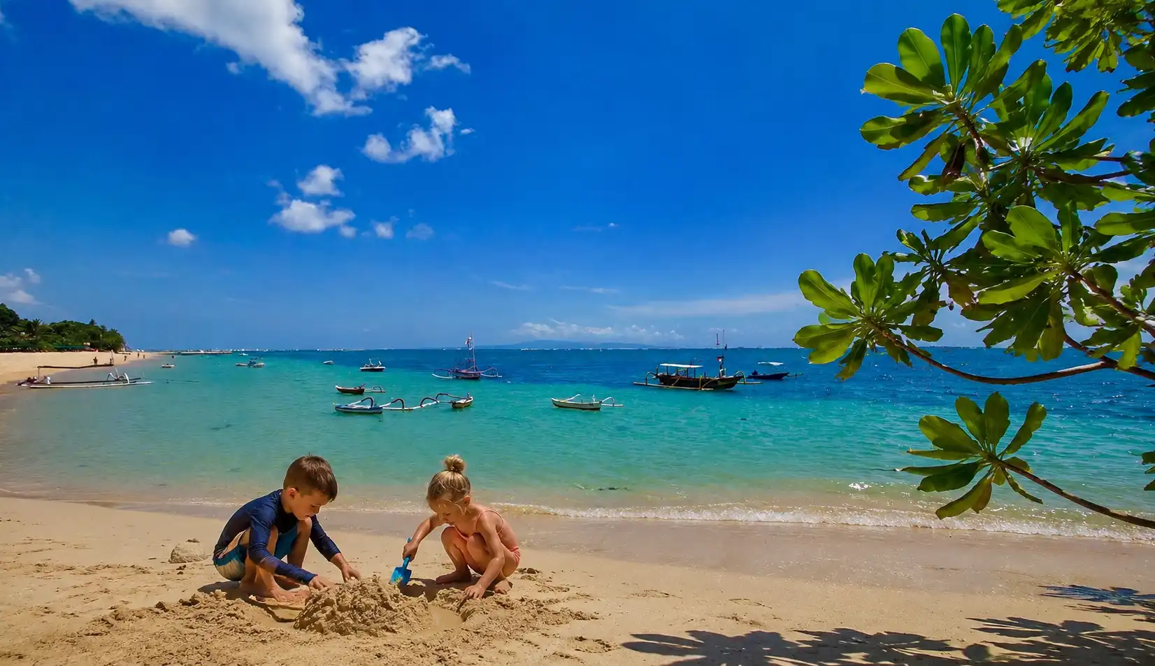 Calm shallow water at Sanur Beach with children playing