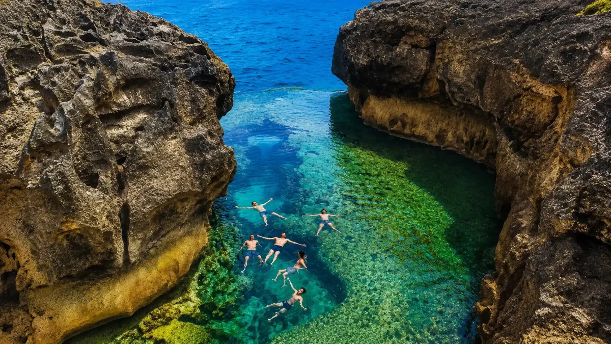 angel billabong - klungkung interesting places to visit - bali touristic Tourists enjoying Angel’s Billabong in Nusa Penida with its natural infinity pool and rugged coastal cliffs.