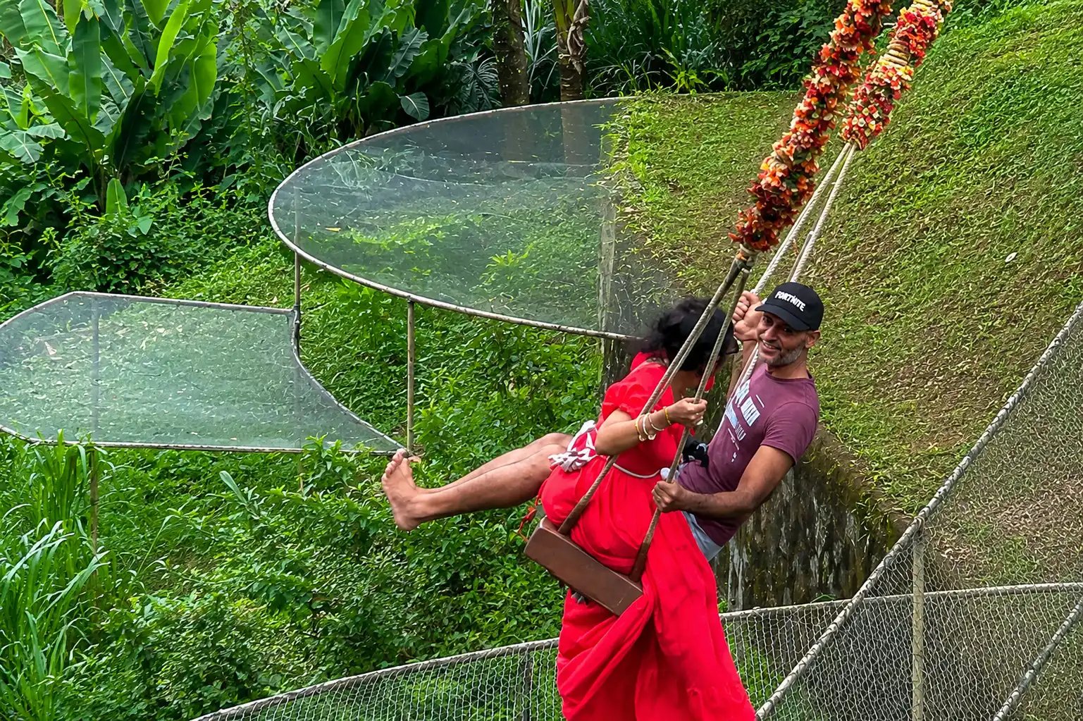 A couple sitting together on a high canyon swing, soaring over a lush tropical jungle valley, a classic romantic option for things to do in bali for couples. | balitouristic.com