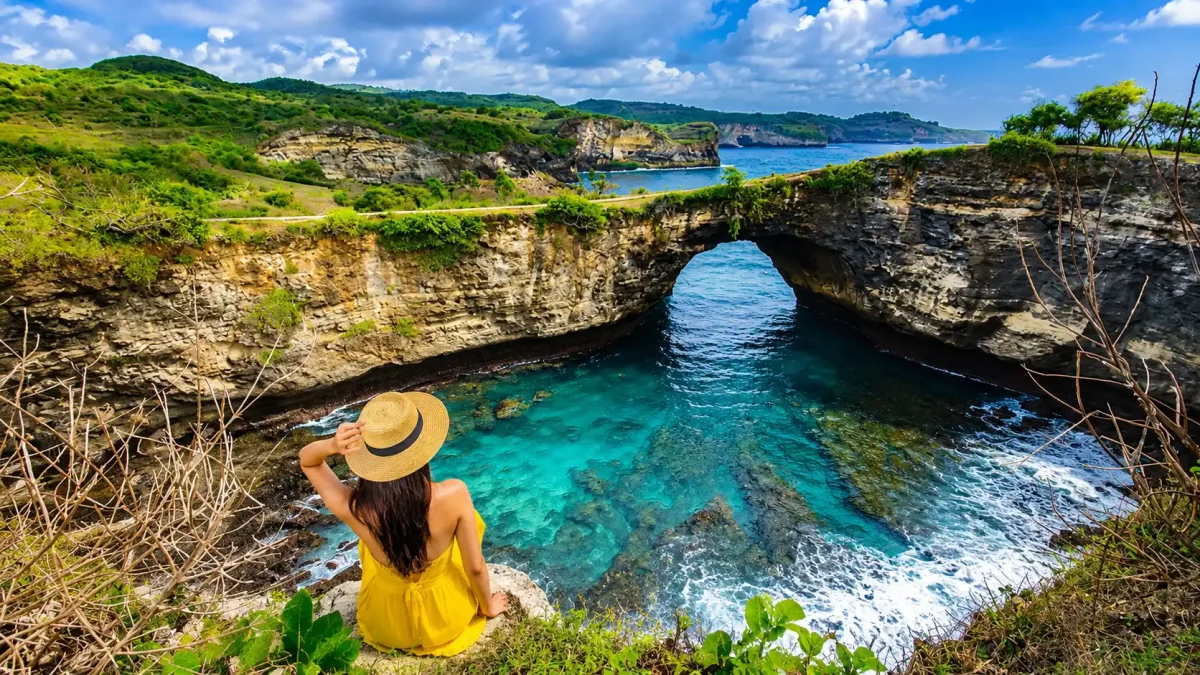 Tourists admiring the natural rock arch and turquoise waters at Broken Beach in Nusa Penida.