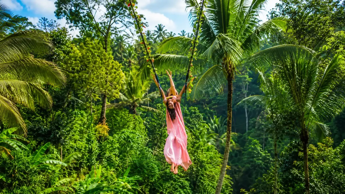 A traveler enjoying a jungle Bali swing Ubud at Uma Pakel Agro Tourism, soaring above lush rice terraces, tropical palm trees, and scenic valleys while experiencing one of Ubud’s most iconic adventure attractions.