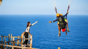 Adventure seekers enjoying paragliding in Bali, soaring high above crystal-clear ocean waters with colorful parachutes, breathtaking coastal views, tropical beaches, and an exciting water sports atmosphere.