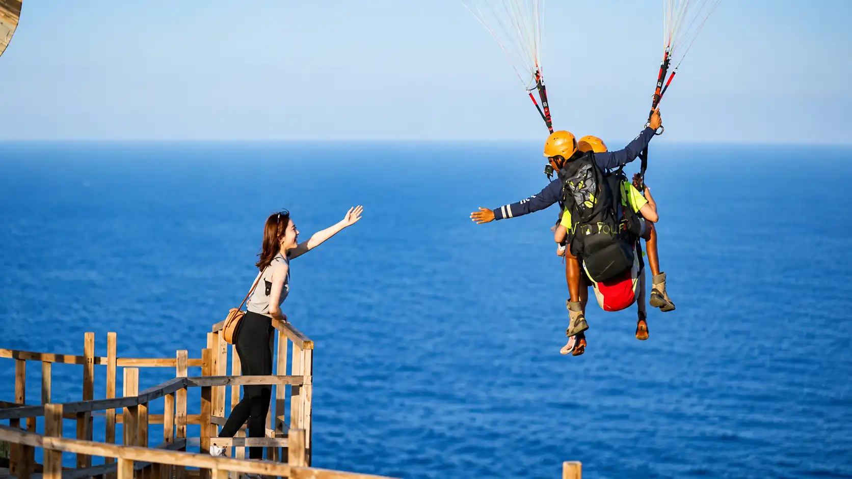 Adventure seekers enjoying paragliding in Bali, soaring high above crystal-clear ocean waters with colorful parachutes, breathtaking coastal views, tropical beaches, and an exciting water sports atmosphere.