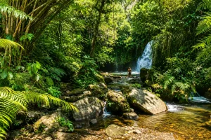 A beautiful multi-tiered mountain stream flowing over dark volcanic boulders from a scenic tropical drop at Yeh Hoo Waterfall.