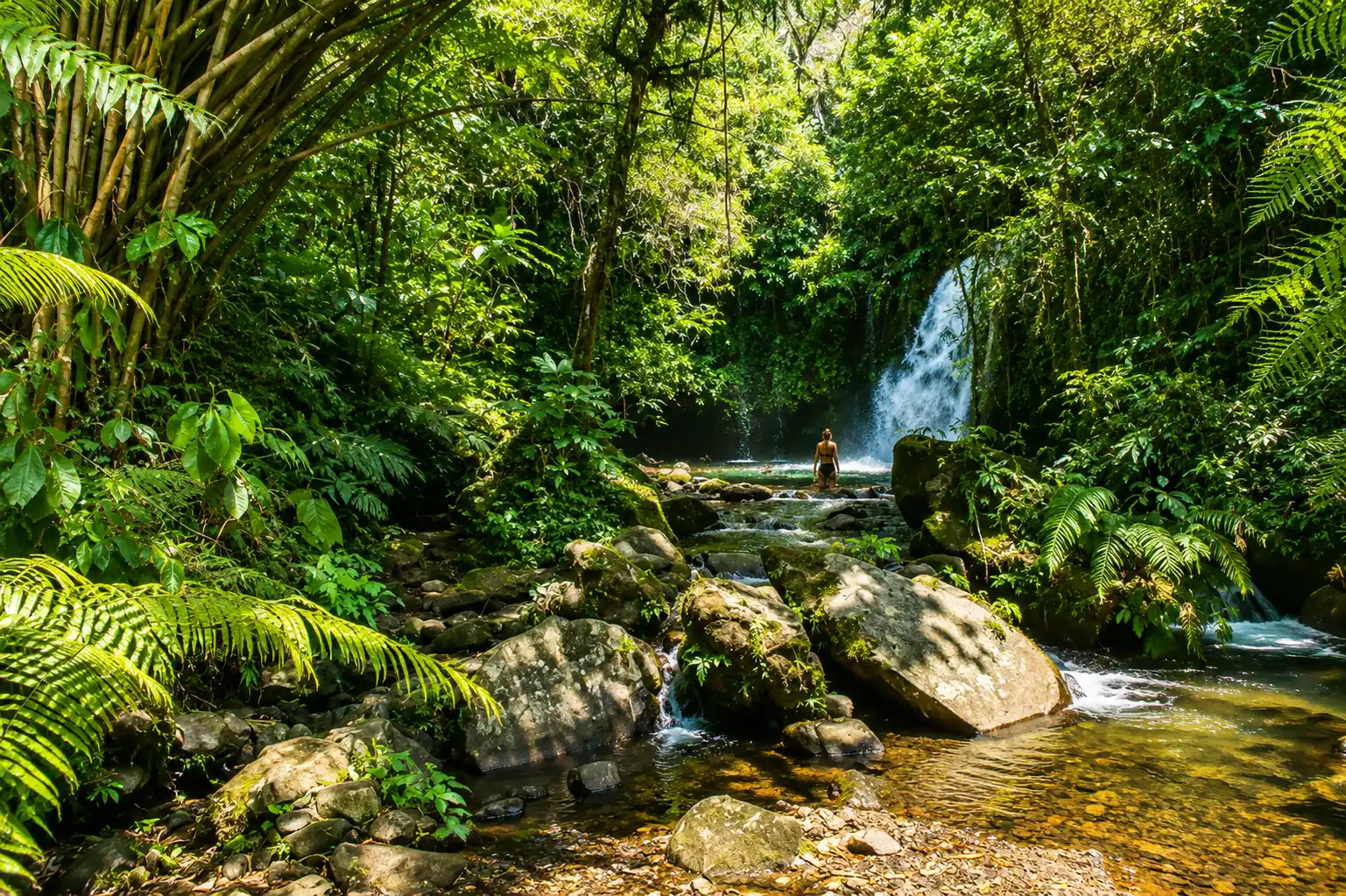 A beautiful multi-tiered mountain stream flowing over dark volcanic boulders from a scenic tropical drop at Yeh Hoo Waterfall.