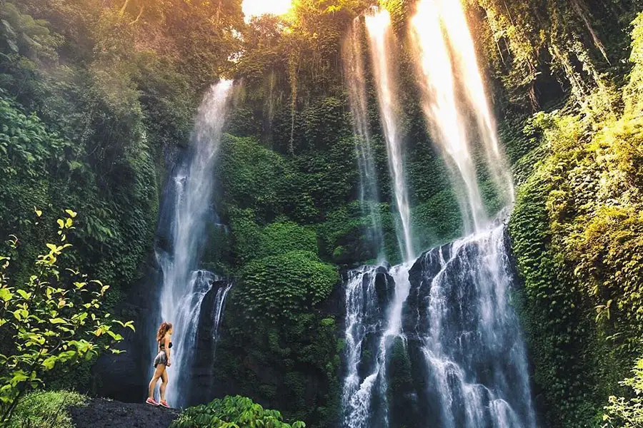 Woman admiring the breathtaking beauty of Sekumpul Waterfall in North Bali.