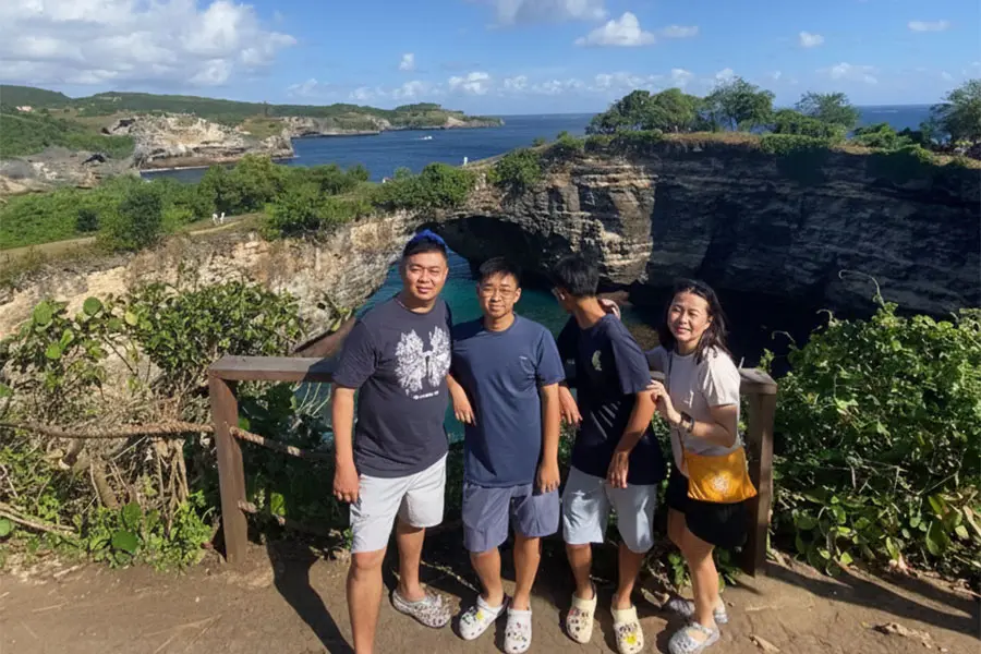 A family posing for a photo behind a wooden railing with the natural rock bridge in the background.