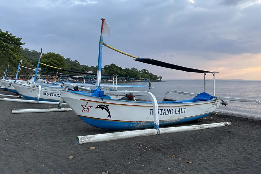 Traditional jukung boats lined up on the black sand of Lovina Beach at sunrise