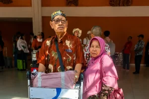An elderly couple standing with a luggage trolley at the terminal arrival area, waiting for their pre-booked bali airport shuttle.