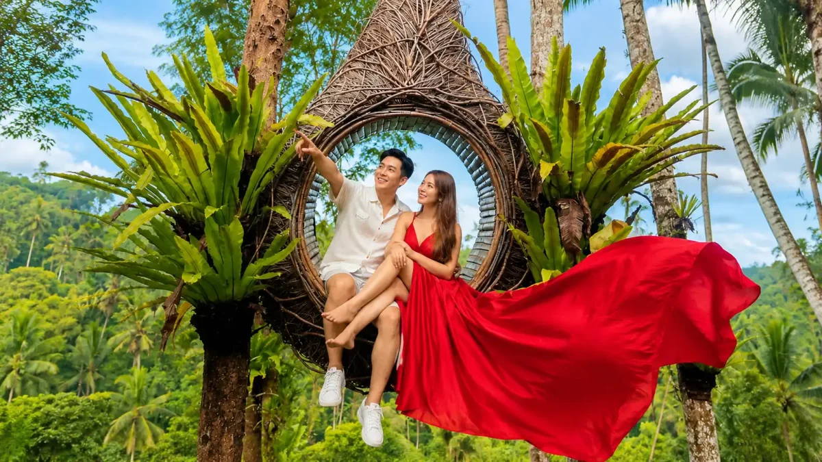Couple sharing a romantic moment on a giant swing overlooking Bali’s tropical landscape.