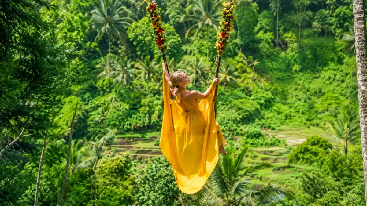 Woman enjoying a giant jungle swing with breathtaking tropical views in Bali.