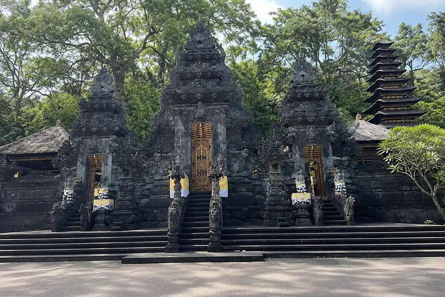 The intricate dark volcanic stone split gates of a Balinese Hindu temple courtyard.