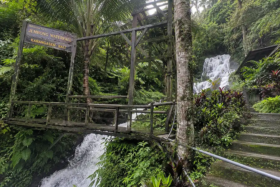 An old wooden footbridge and concrete stairs leading toward a tropical jungle waterfalAn old wooden footbridge and concrete stairs leading toward a tropical jungle waterfall.l.