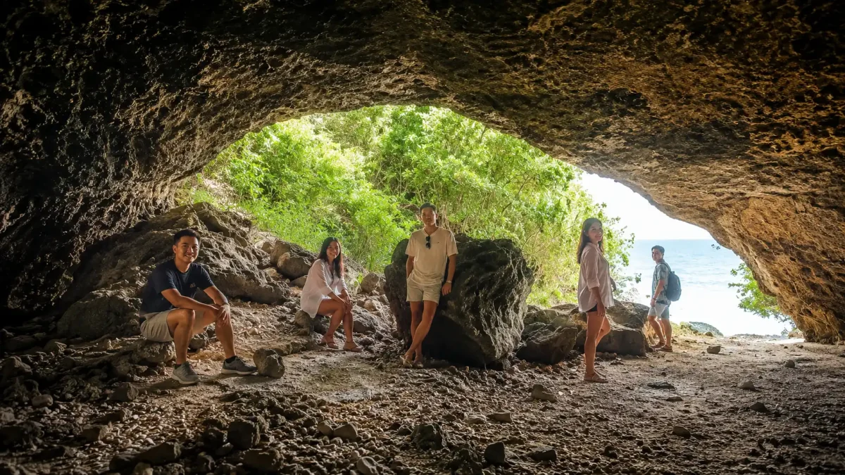 Tourist exploring the natural sea cave at Lumangan Beach surrounded by rugged limestone cliffs.