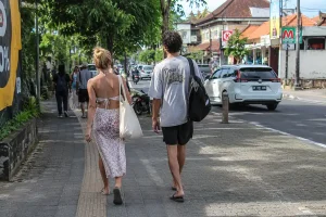 A man and woman walking down a paved sidewalk in casual streetwear, showcasing comfortable and simple travel outfits in bali.