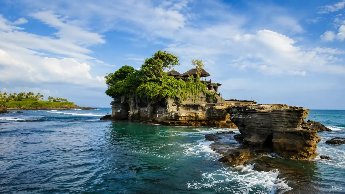 Scenic view of Tanah Lot Temple surrounded by crashing waves at sunset in Bali.