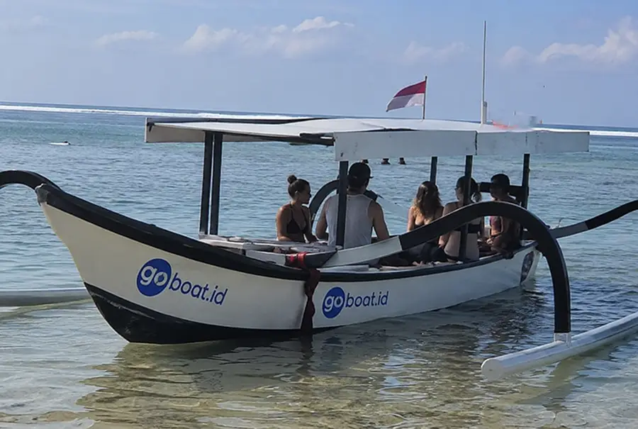 Passengers board a wooden outrigger boat to skip Bali traffic.