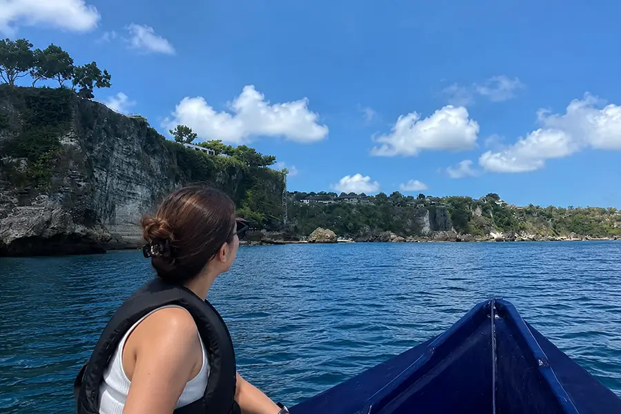 A passenger looking at coastal cliffs while riding a boat Canggu to Uluwatu.