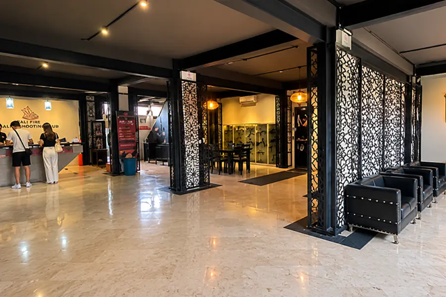 A spacious indoor reception area with leather armchairs, decorative black screens, and warm lighting.