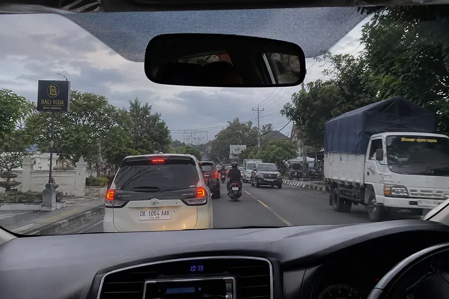 Dashboard view during a private car transfer from Sanur to Uluwatu.