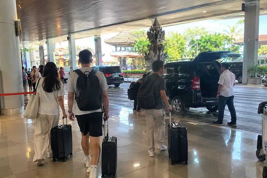 Passengers leaving Bali Airport arrival area with luggage
