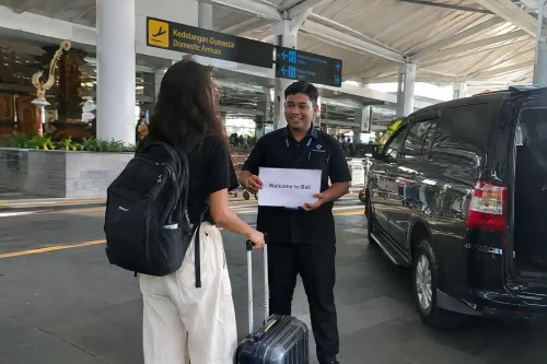 Private driver holding welcome sign for Bali airport to Sidemen transfer.