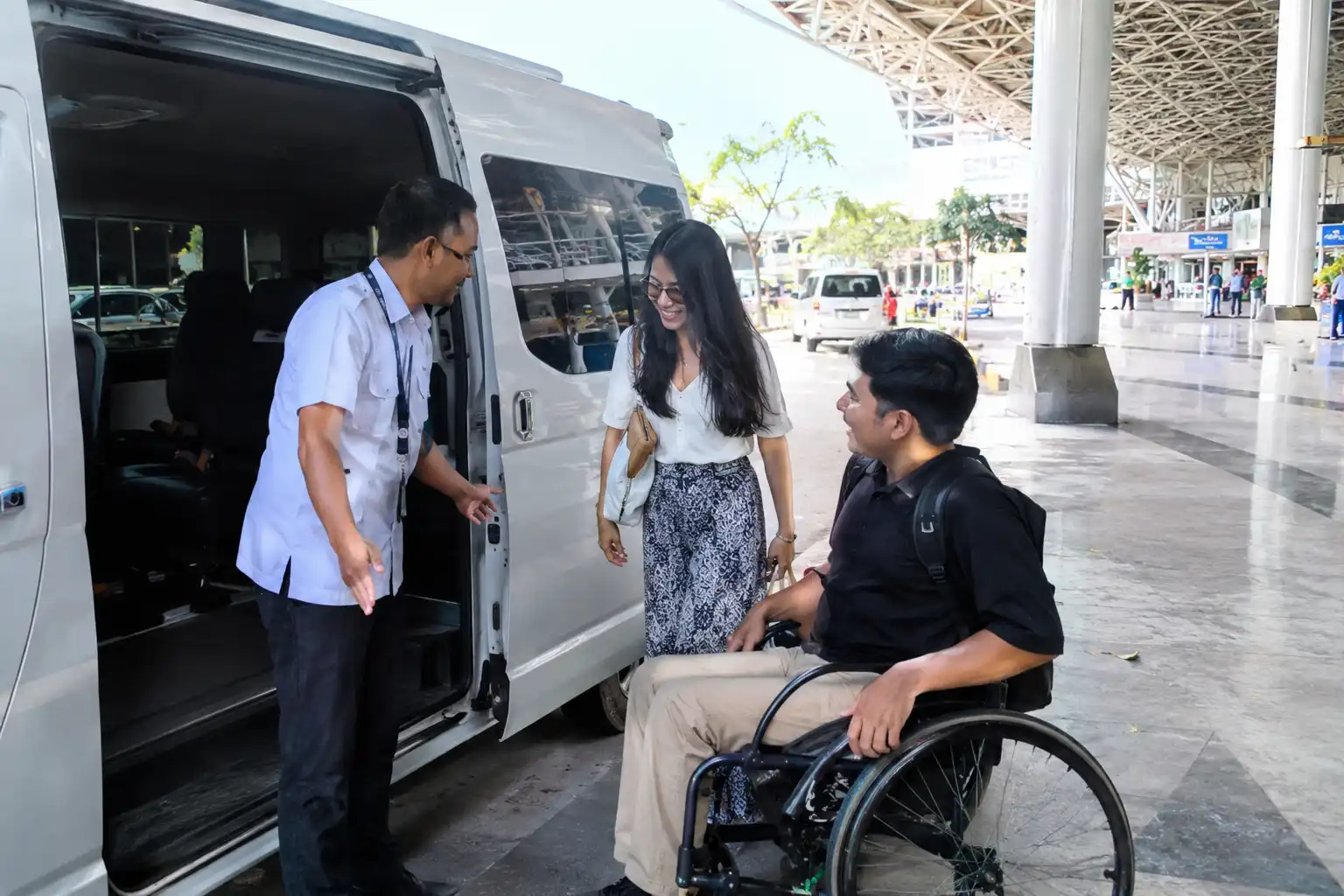 Driver assisting wheelchair traveller before a Bali airport transfer