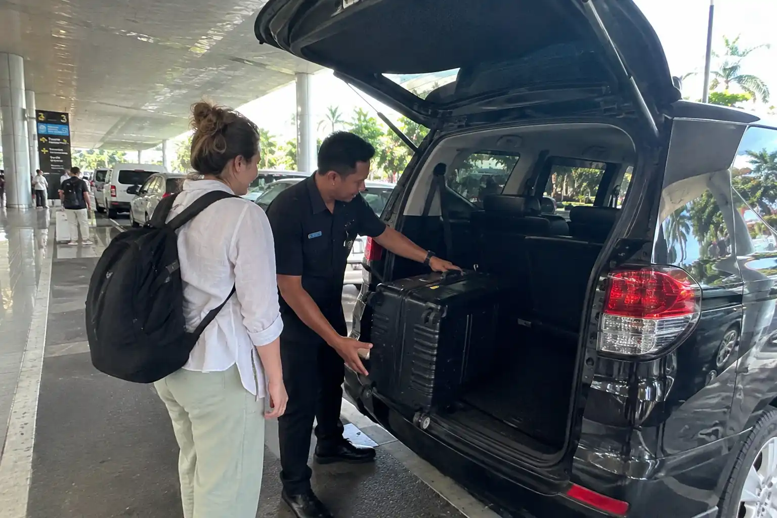 Bali airport transfer driver helping a traveller with luggage.