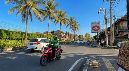 Grab driver on a scooter offering Bali airport transfer to Sanur.
