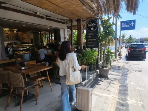 A tourist with luggage walking into a coffee shop